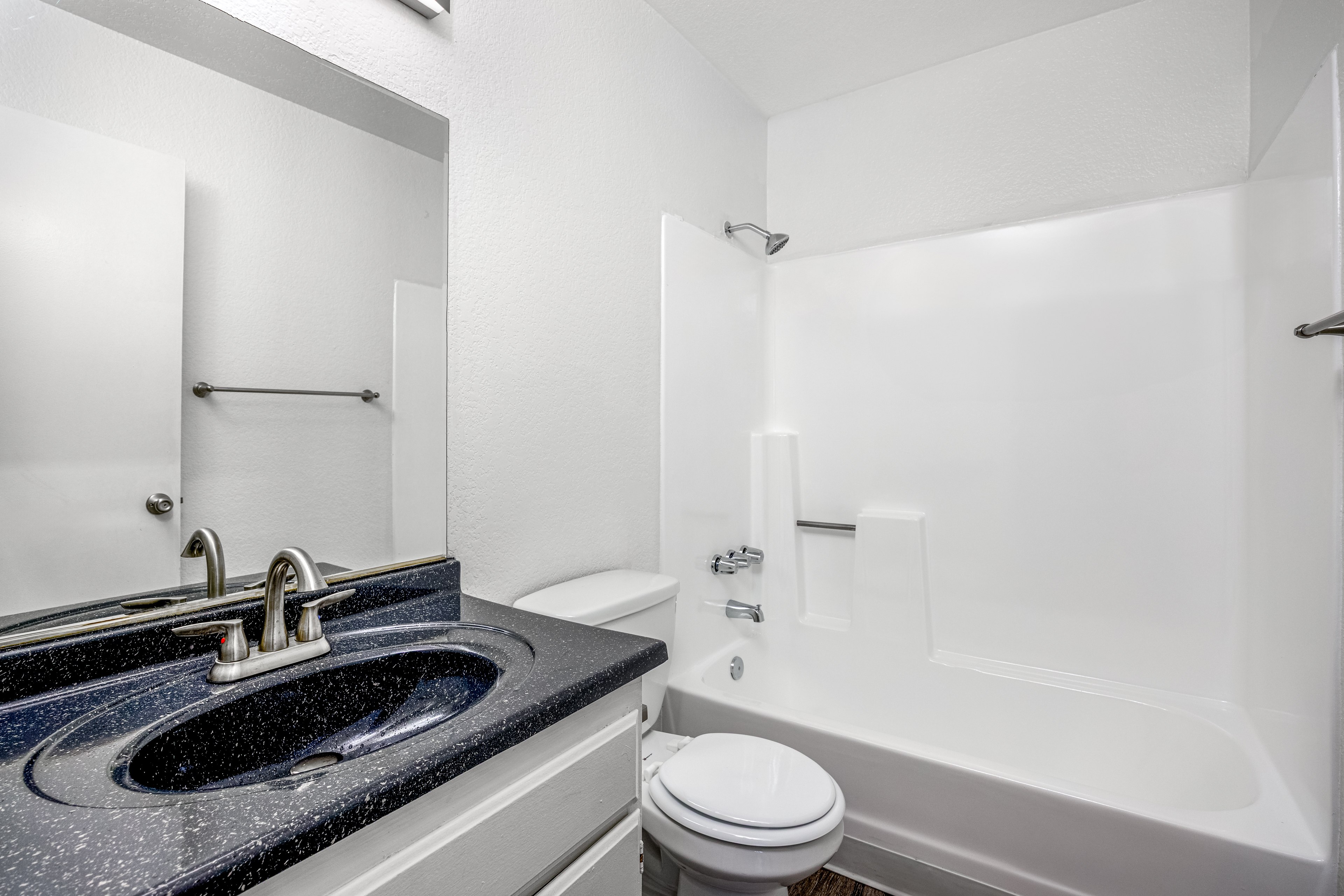 A bathroom with a black granite countertop and white fixtures.